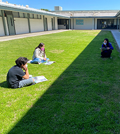 Students sitting on grass outside school building